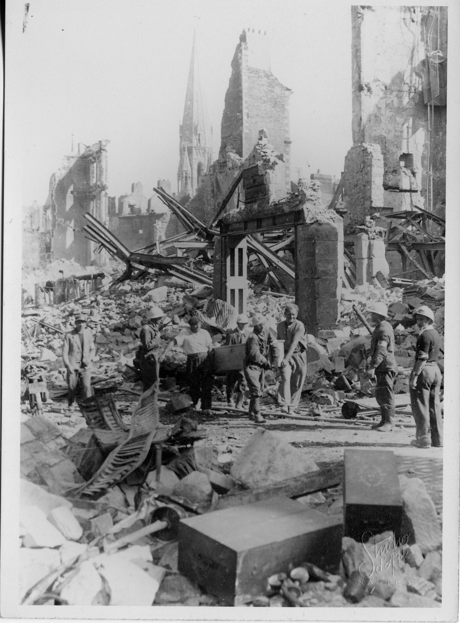 Rue du Calvaire, un groupe de la Défense passive dégage un cercueil devant les ruines du magasin 