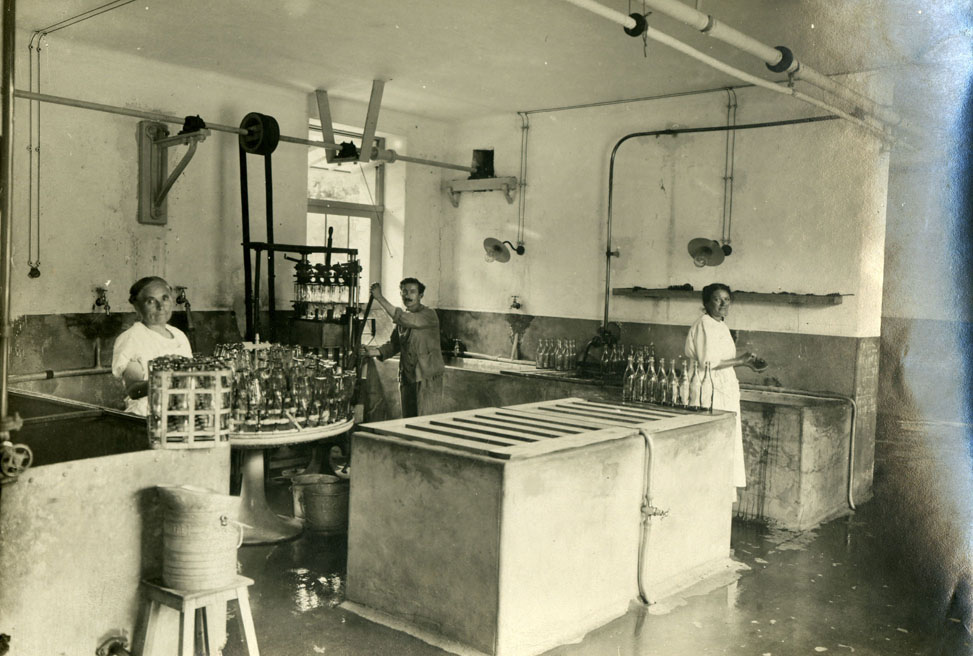 Laiterie municipale, des employés posent à côté de machines et de bacs servant au nettoyage et au remplissage des bouteilles (26Fi622)
