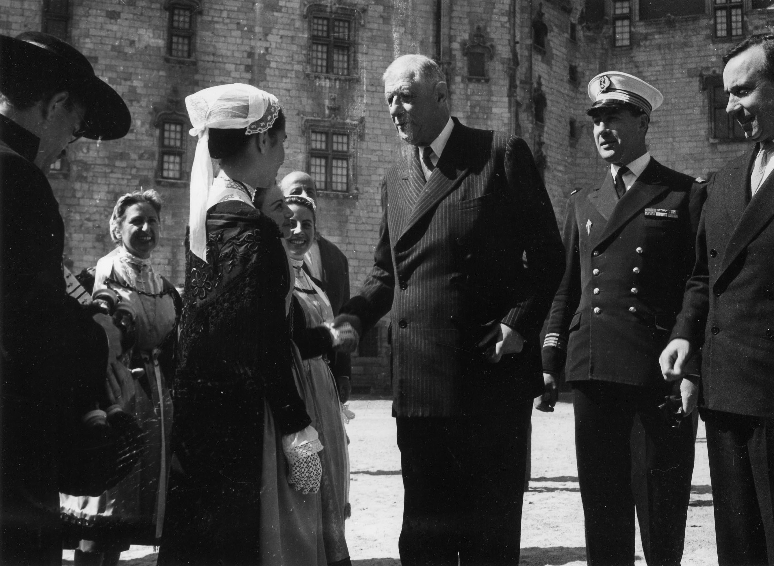 Le général de Gaulle, accompagné de Michel Debré, Premier ministre, et du capitaine de corvette Le Flohic, aide de camp, rencontre dans la cour du château des ducs de Bretagne le groupe folklorique 
