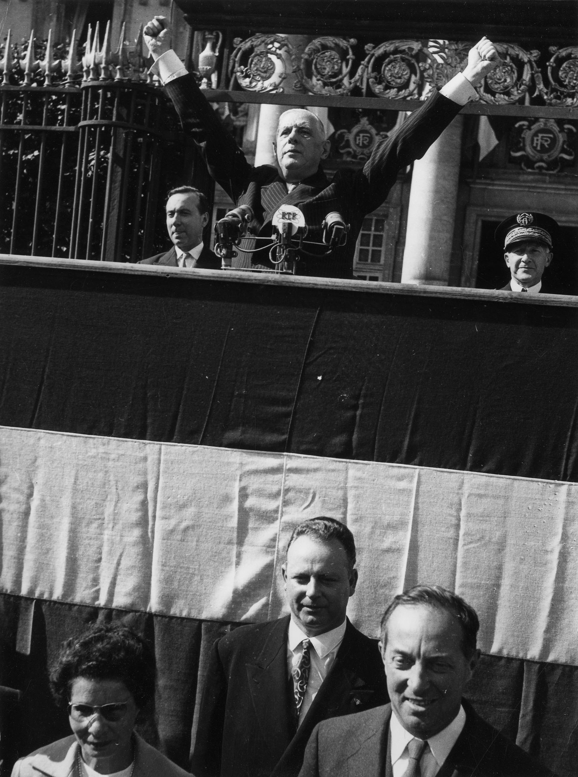 Le général de Gaulle, bras levés lors de son discours à la tribune de la préfecture, le 10 septembre 1960. Derrière lui, Michel Debré, Premier ministre, et Pierre Trouillé, préfet de Loire-Atlantique. Au pied de la tribune Nafissa Sid Cara, secrétaire d'état (79Z12 - Fonds Régis Routier)