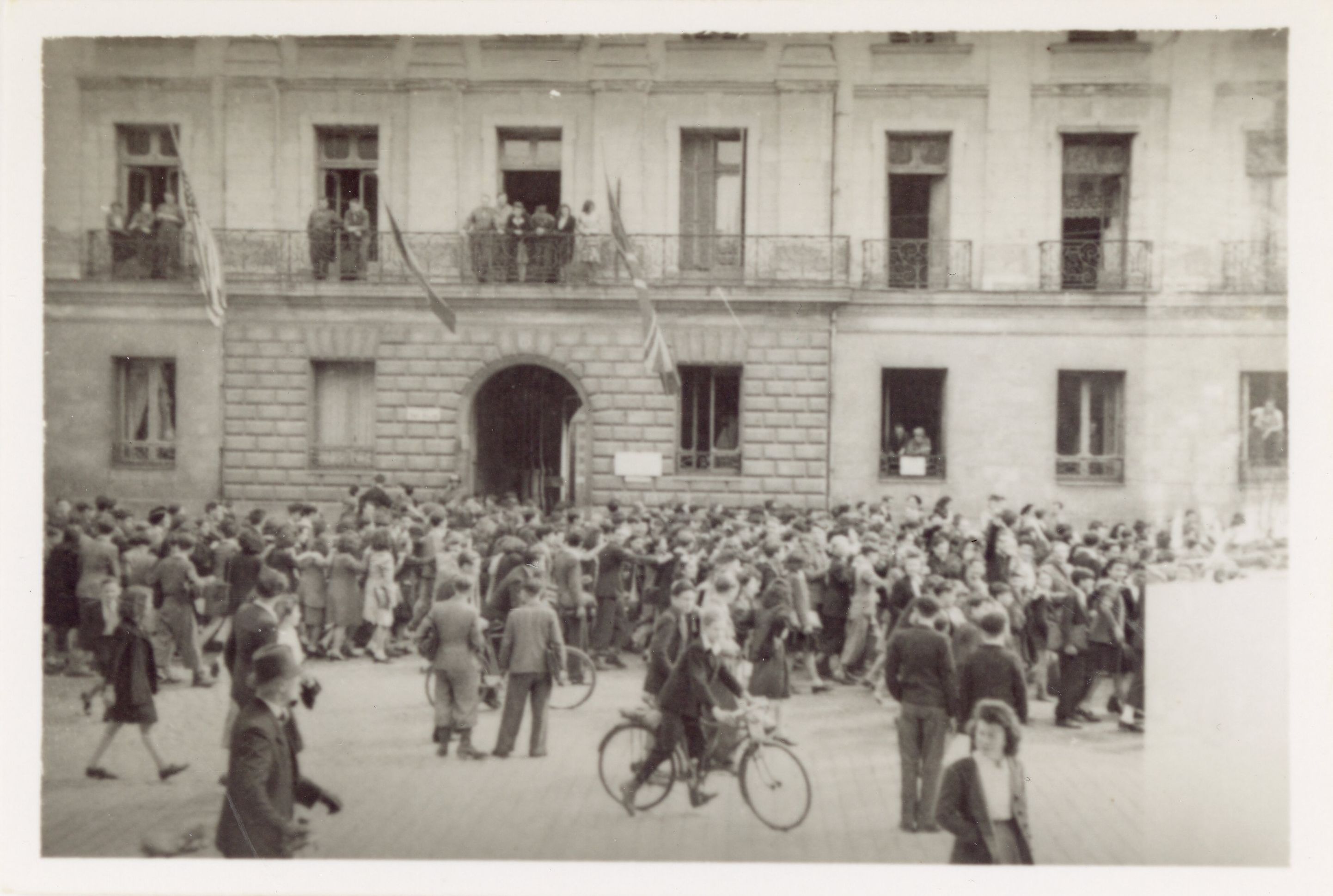 Place de l'Oratoire, des drapeaux alliés flottent aux fenêtres des immeubles. À leur pied, une foule compacte est en marche (151Z9)