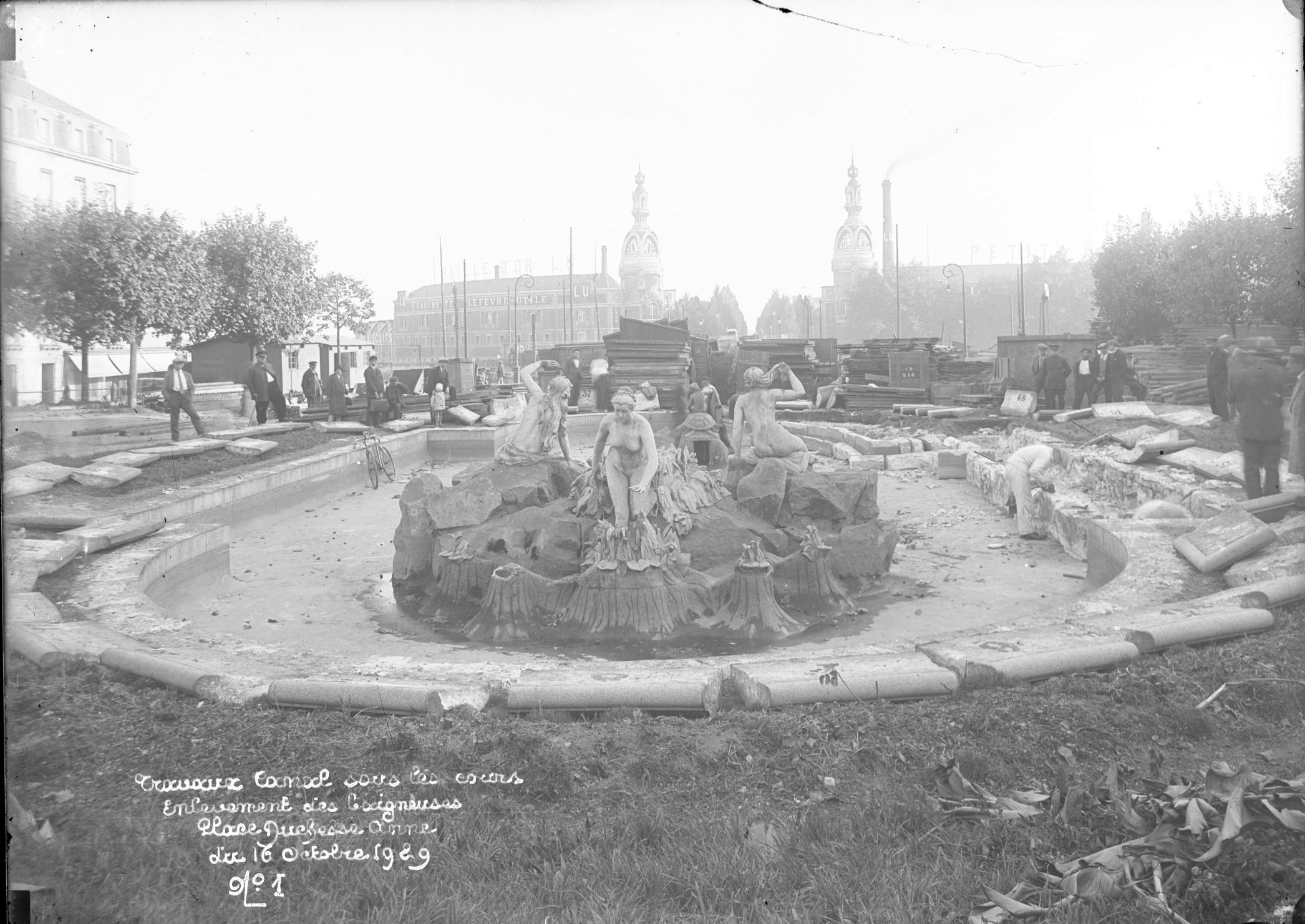 En prévision des travaux de construction du canal Saint-Félix, la fontaine de la place de la Duchesse-Anne est démontée à la fin de l’année 1929. Des passants observent les ouvriers au travail (13Fi3790)