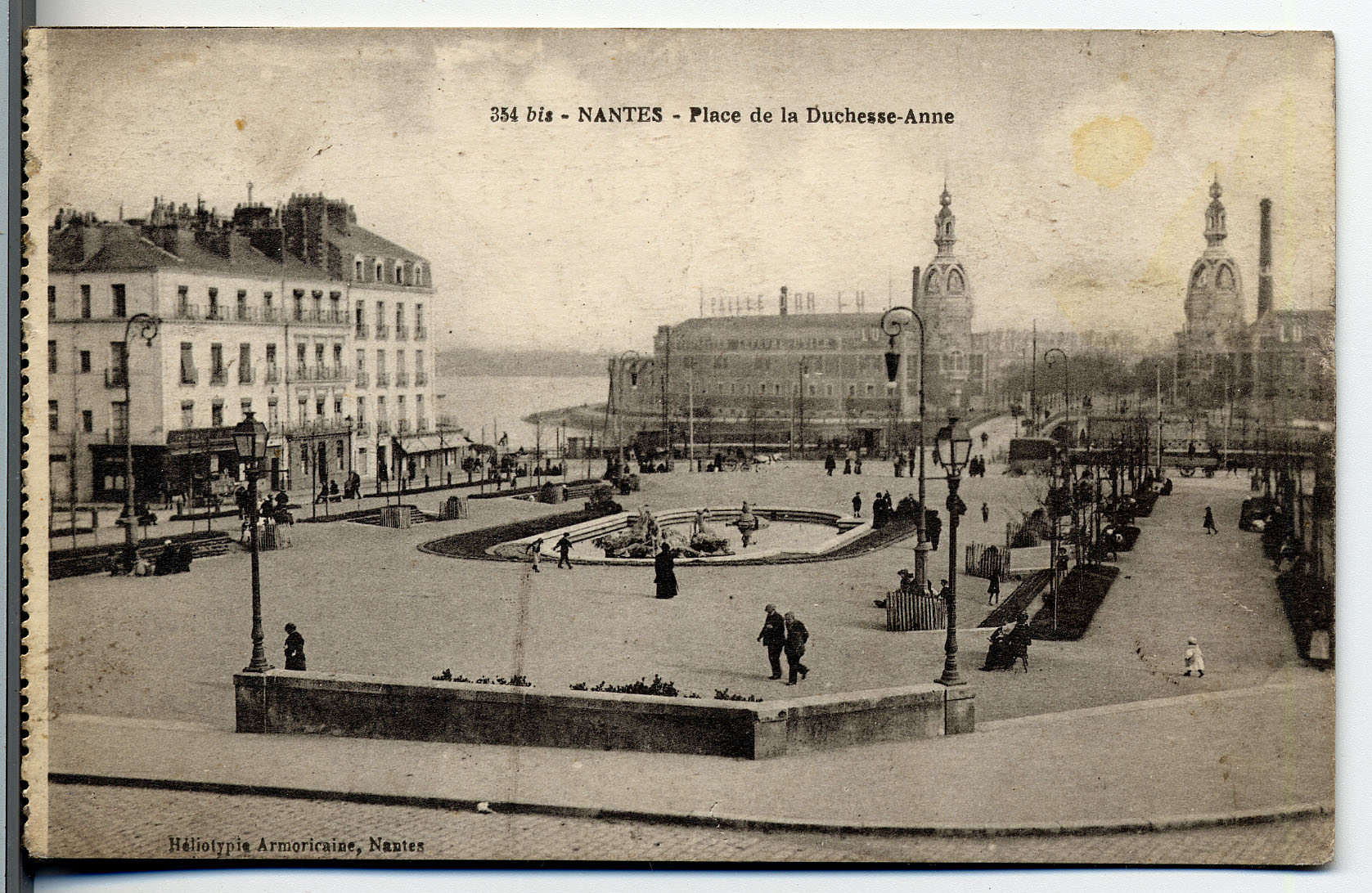 Dans le cadre des travaux d’embellissement de la ville entrepris par la municipalité, la place est transformée en square en 1908. Des parterres y sont aménagés, ainsi qu’une fontaine. Au second plan, un bras de la Loire, le pont de la Rotonde et les deux tours de l’usine Lefèvre-Utile (9Fi725)