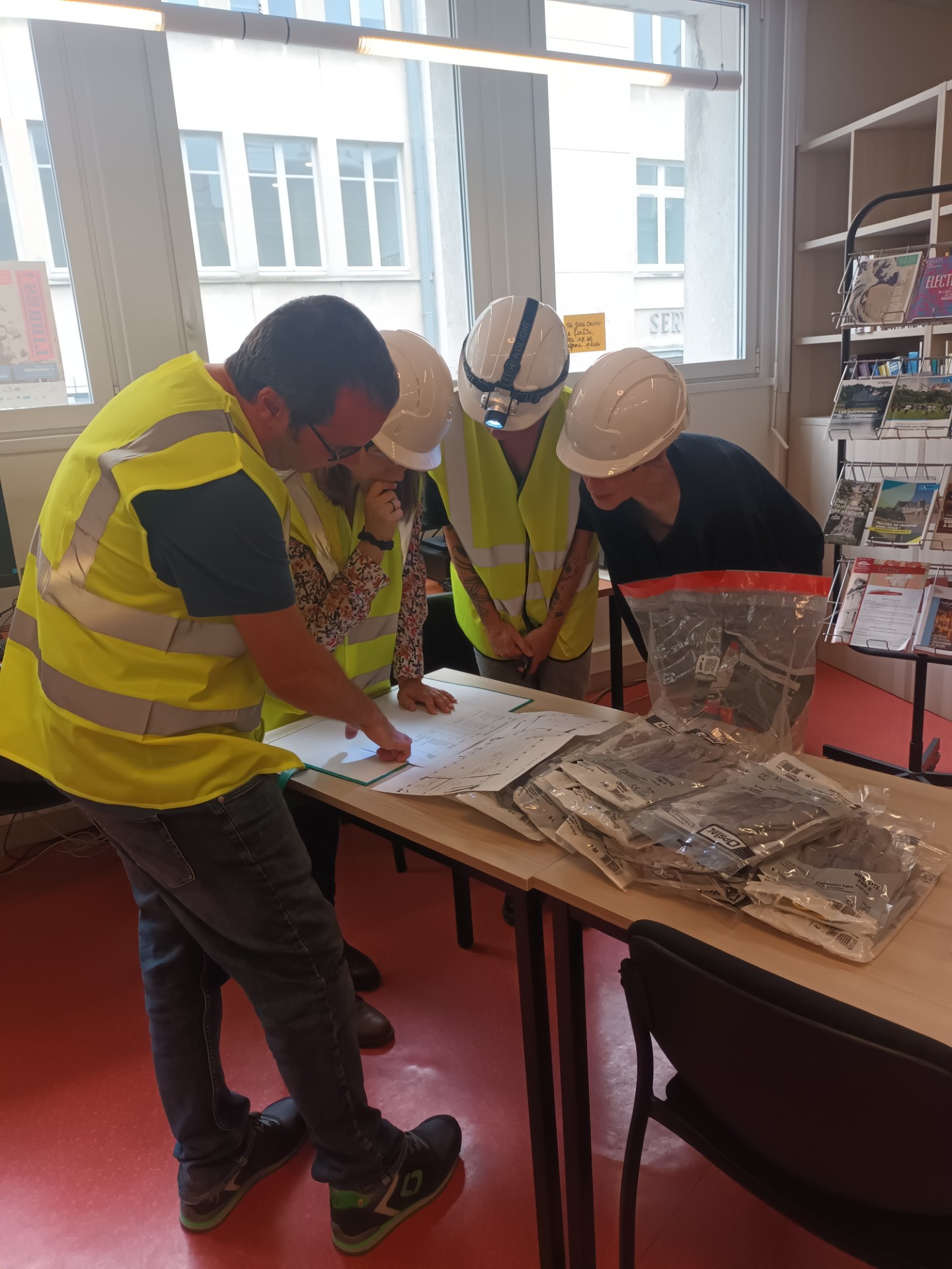 Équipement de sécurité revêtu, chaque groupe examine la liste des cotes à évacuer et le plan du magasin de conservation pour se répartir les rôles avant le début de l'exercice